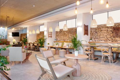 a restaurant with tables and chairs and a stone wall at Can Lluc Suites & Villas Ibiza's Peaceful Getaway in Sant Rafael de Sa Creu