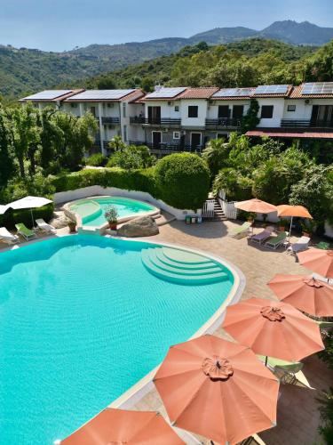 a large swimming pool with umbrellas in a resort at Eden Park Hotel in Marina di Campo