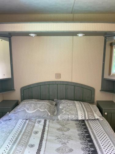 un grande letto in una camera da letto con due comodini di Mobil Home 40 4-6 personnes, nature, piscine parc du Pilat a Saint-Appolinard