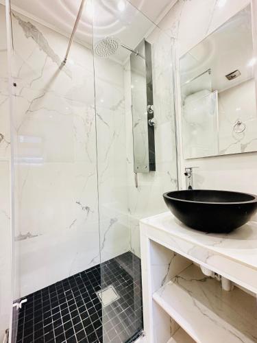 La salle de bains est pourvue d'une douche en verre et d'un lavabo noir. dans l'établissement Pretty Central flat in Paris, à Paris
