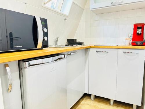 une cuisine avec des armoires blanches et un micro-ondes dans l'établissement Pretty Central flat in Paris, à Paris