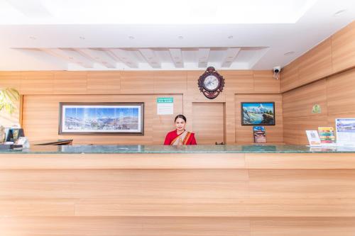 a woman is standing behind a counter in a waiting room at Moonlight Resort and Spa in Pokhara