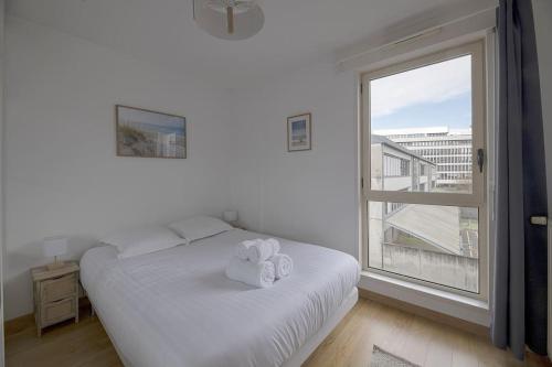 une chambre avec un lit blanc avec deux serviettes dessus dans l'établissement Le Mabilay, à Rennes