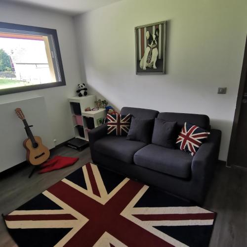 - un salon avec un canapé noir et une guitare dans l'établissement Villa avec piscine, à Cusy