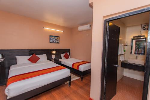 a hotel room with two beds and a bathroom at Moonlight Resort and Spa in Pokhara