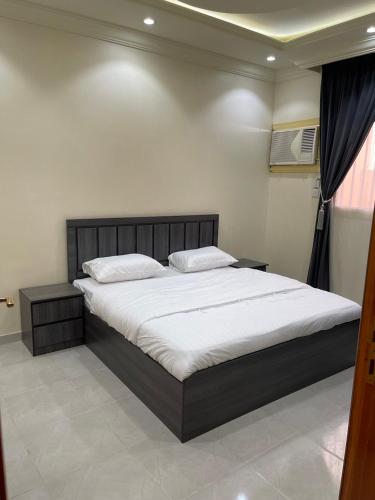 Un dormitorio con una cama grande con sábanas blancas. en نزل الوسام 2, en Taif
