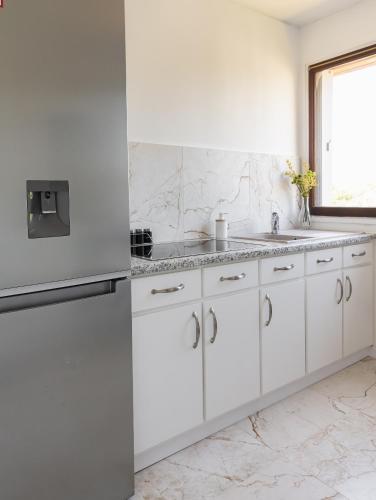 une cuisine blanche avec des armoires blanches et une fenêtre dans l'établissement Appartement 3 chambres, à Fréjus