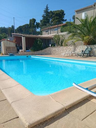 une grande piscine bleue devant une maison dans l'établissement Studio cosy avec piscine les Accatine 2, à Marseille
