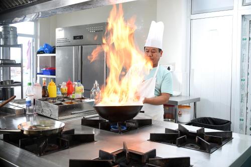 a chef is cooking food in a wok with flames at Hotel Vistara in Kathmandu