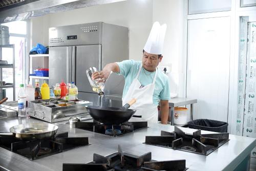 a man in a kitchen preparing food in a wok at Hotel Vistara in Kathmandu