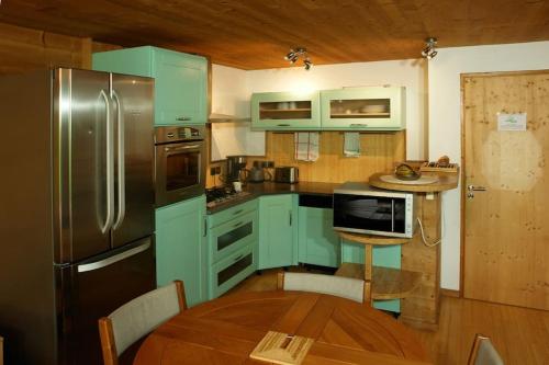 La cuisine est équipée de placards bleus, d'une table et d'un réfrigérateur. dans l'établissement Très beau T3 en rez de jardin à 5 minutes de la station de Carroz, à Arâches-la-Frasse