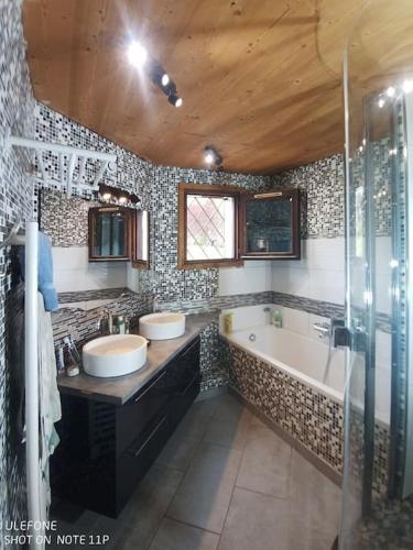 une salle de bain avec deux lavabos et une baignoire dans l'établissement Très beau T3 en rez de jardin à 5 minutes de la station de Carroz, à Arâches-la-Frasse