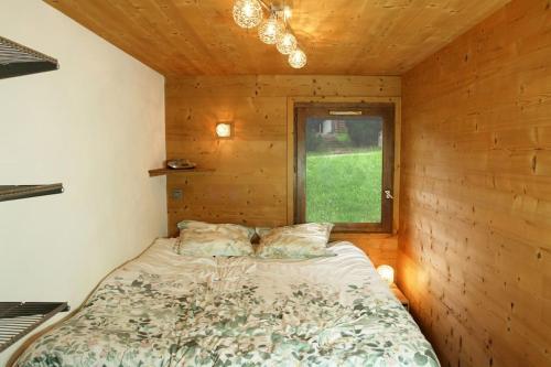 Ce lit se trouve dans une chambre en bois dotée d'une fenêtre. dans l'établissement Très beau T3 en rez de jardin à 5 minutes de la station de Carroz, à Arâches-la-Frasse