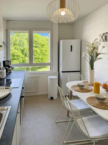 une cuisine avec une table avec des chaises et un réfrigérateur dans l'établissement Chantilly, à Rennes