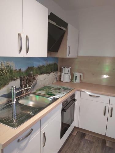 a kitchen with white cabinets and a sink at Wohnung Sonnenschein Wolgast in Wolgast