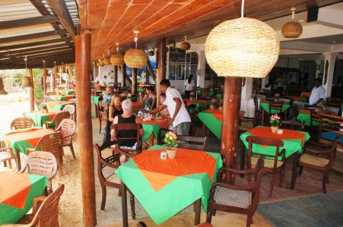 a restaurant with tables and chairs and people sitting at them at Ritas Hotel in Hikkaduwa