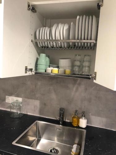- une cuisine avec un évier et une étagère avec de la vaisselle dans l'établissement Charmant duplex Metro Raspail jardin du Luxembourg, à Paris