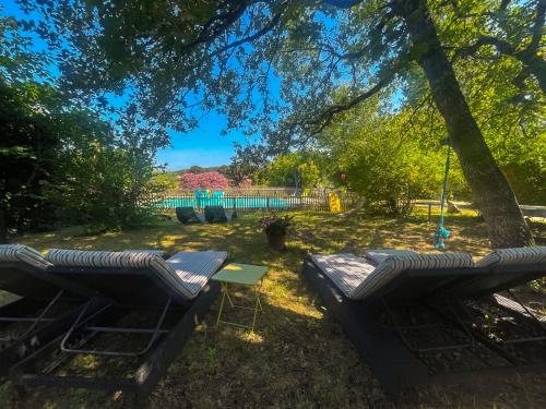two chairs and a table under a tree at Appartement dans un Mas provençal in Allan