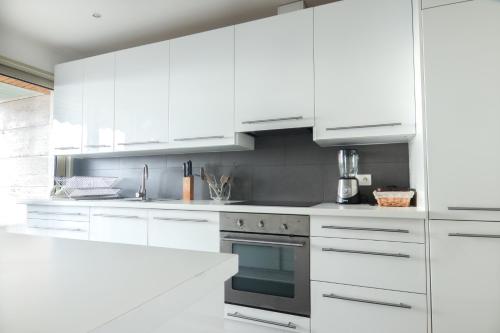 - une cuisine blanche avec des placards blancs et un four dans l'établissement Magnifique vue mer, grande terrasse et piscine, à Cannes