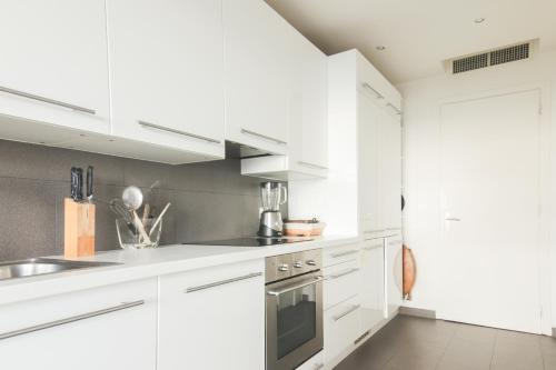 une cuisine blanche avec des armoires blanches et un évier dans l'établissement Magnifique vue mer, grande terrasse et piscine, à Cannes