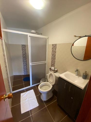 a bathroom with a toilet and a sink and a mirror at Hospedaje La Casona de San Francisco in Monguí