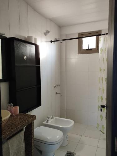 a white bathroom with a toilet and a sink at Takú Huasi in La Rioja
