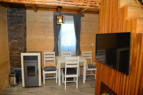 a dining room with a table and chairs and a television at Zagrad Homes in Zabljak in Žabljak