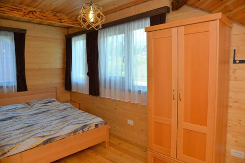 a bedroom with a bed and a cabinet and windows at Zagrad Homes in Zabljak in Žabljak