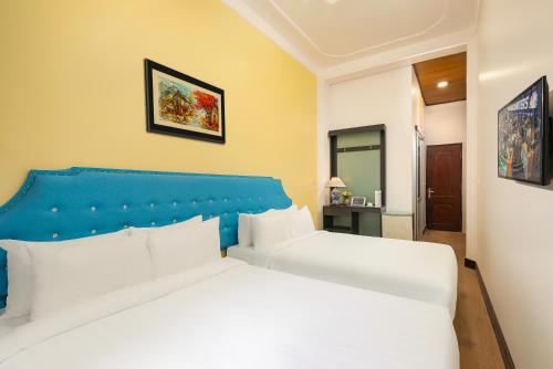 a bedroom with a white bed with a blue headboard at Little Hanoi Old Quarter Hostel in Hanoi