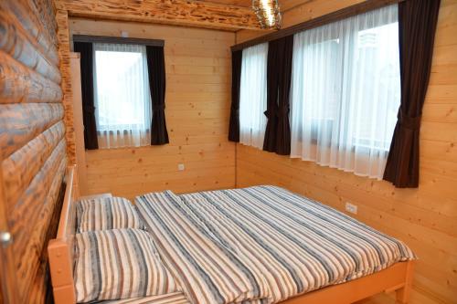 a bed in a cabin with two windows at Zagrad Homes in Zabljak in Žabljak