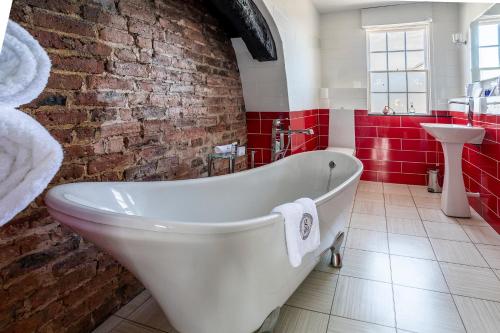 a white bath tub in a bathroom with a brick wall at Georgian House Hotel in Whitehaven
