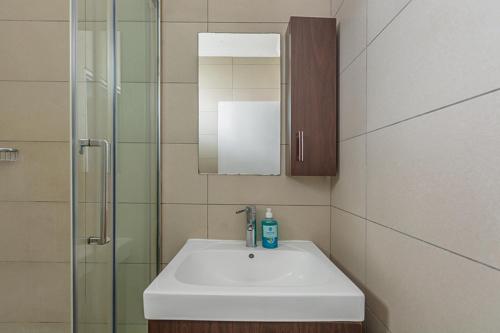 un bagno con lavandino e doccia in vetro di Modern Heritage Condo a Fourways