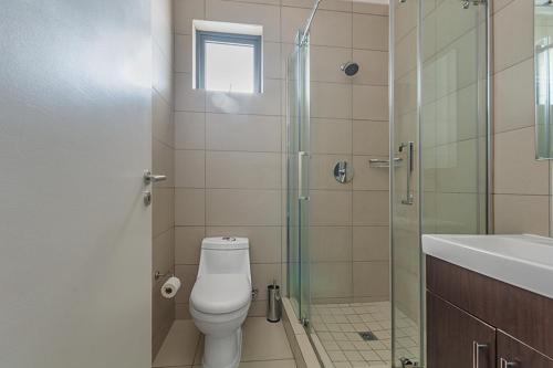 a bathroom with a toilet and a glass shower at Modern Heritage Condo in Fourways