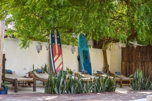 two surfboards leaned up against a wall next to chairs and sidx sidx at Badolina Bungalows in Nungwi