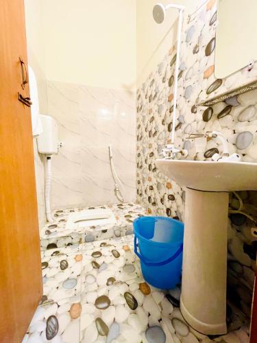 a bathroom with a sink and a toilet with shells on the floor at Airport Hotel Bed & Rest in Karachi