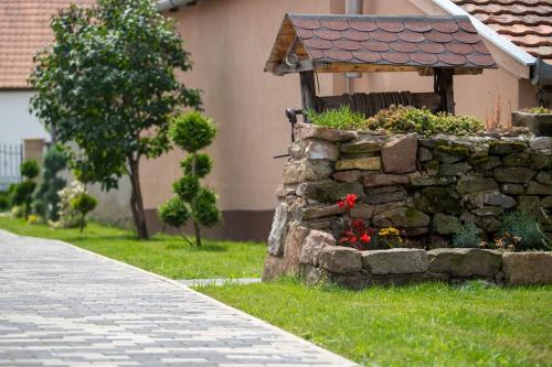 a stone wall with flowers in front of a house at Kövirózsa Vendégház in Cserépfalu