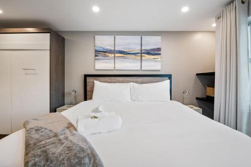 a bedroom with a large white bed with two paintings on the wall at Ski In & Out, Heart of Upper Village, Pool & Hot Tub in Whistler