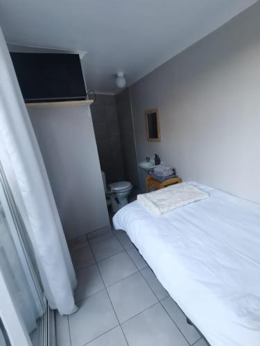 een slaapkamer met een wit bed en een toilet bij Cozy Business overnighter in Bellville