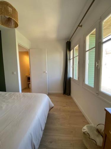 - une chambre avec un lit blanc et 2 fenêtres dans l'établissement Maison de village la digue, à Fabrègues