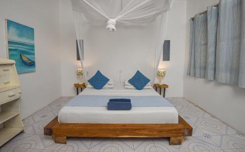 a bedroom with two beds with blue pillows at Badolina Bungalows in Nungwi