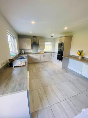 a large kitchen with white cabinets and a tile floor at Valley Lodge 3 BR Retreat in Craigantlet Hills in Belfast