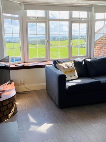 a living room with a blue couch and windows at Valley Lodge 3 BR Retreat in Craigantlet Hills in Belfast