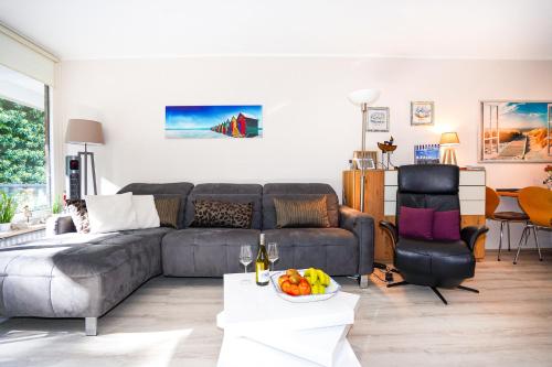 a living room with a couch and a table with a bowl of fruit at Seglernest 204, strandnahe Fewo mit Schwimmbad und Sauna in Timmendorfer Strand