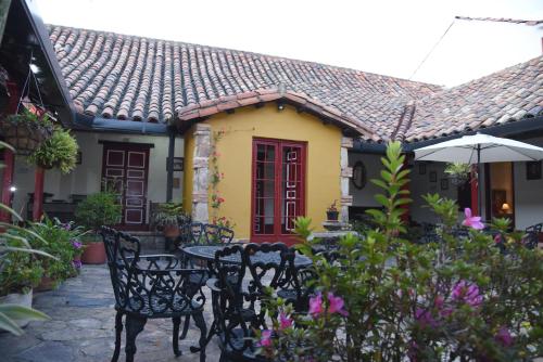 a table and chairs in front of a yellow house at Hotel Cacique Real in Zipaquirá