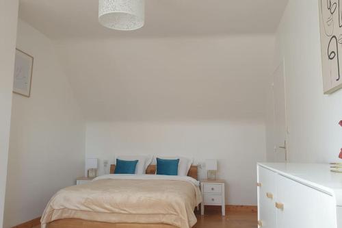 - une chambre blanche avec un lit et des oreillers bleus dans l'établissement La Maison Fleurie, à Josselin