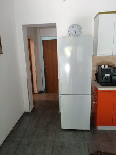a white refrigerator in a kitchen with a clock on the wall at Alternative in Shekvetili