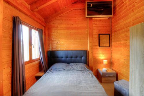 une chambre avec un lit dans une cabane en bois dans l'établissement Maison en bois village entre montagne et mer, à Sari-dʼOrcino