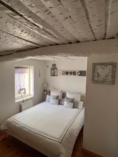 une chambre avec un grand lit avec des draps blancs dans l'établissement Lou Caberoma, à Carcès