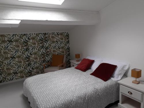 une chambre avec un lit avec deux oreillers rouges dans l'établissement Le petit Gîte de France, à Libourne