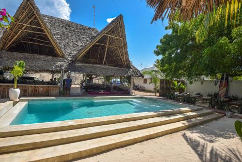 a swimming pool in front of a resort with a building at Badolina Bungalows in Nungwi